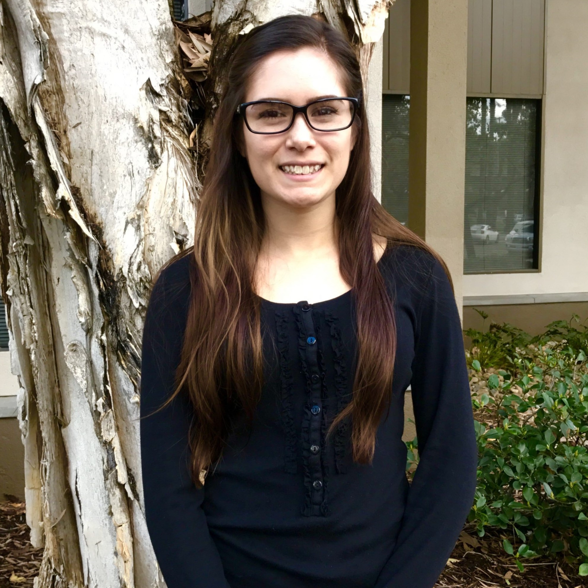 Headshot of former master's student Cindy in front of a peeling bark tree background