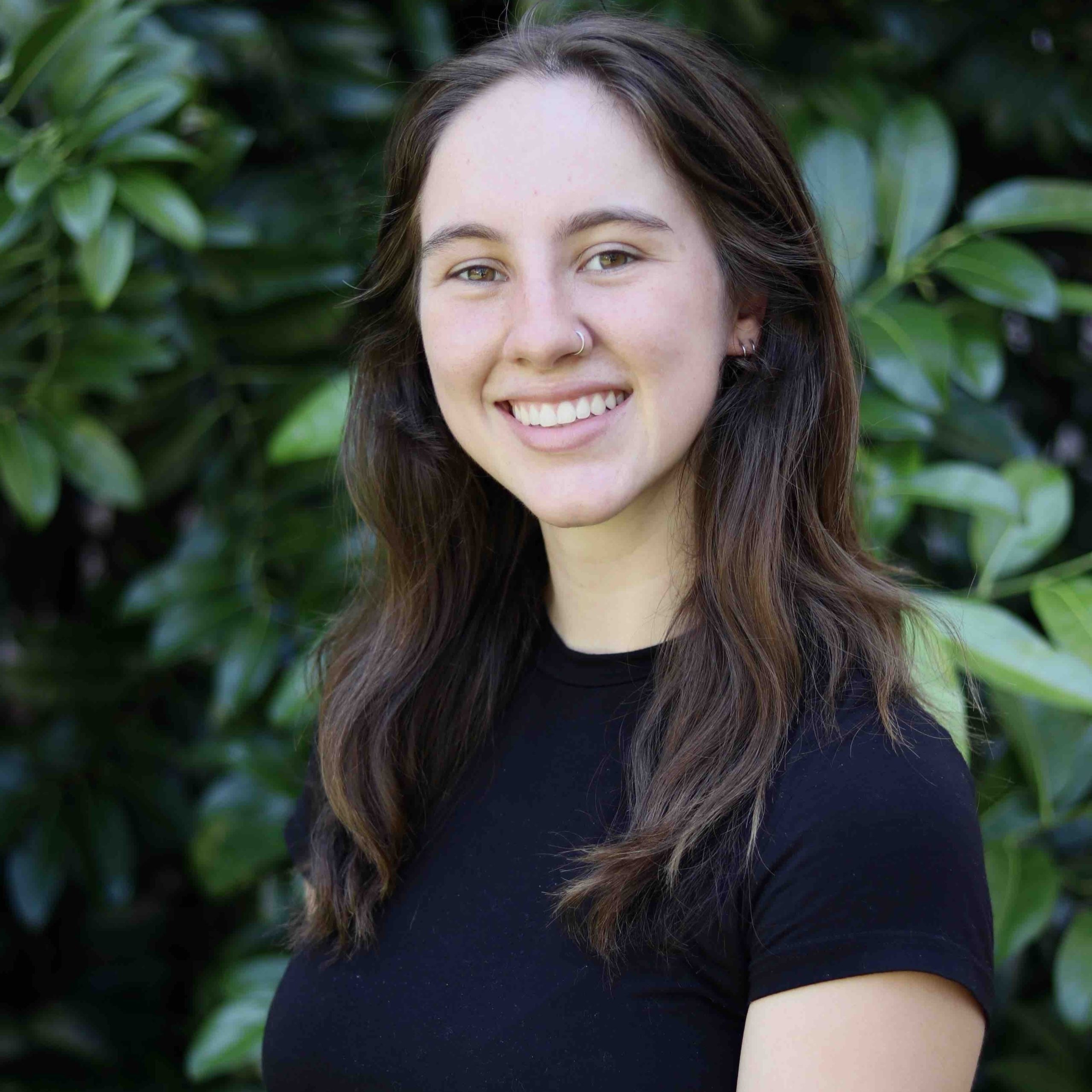 Headshot of research assistant and specialist Hailey with large green leaves in the background