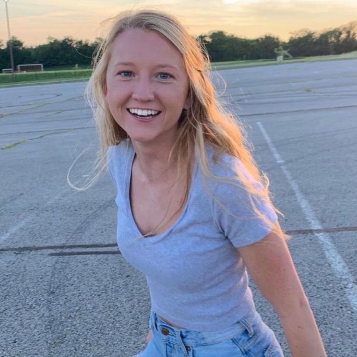 Headshot of former research assistant Lexi in an empty parking lot as the sun sets in the background