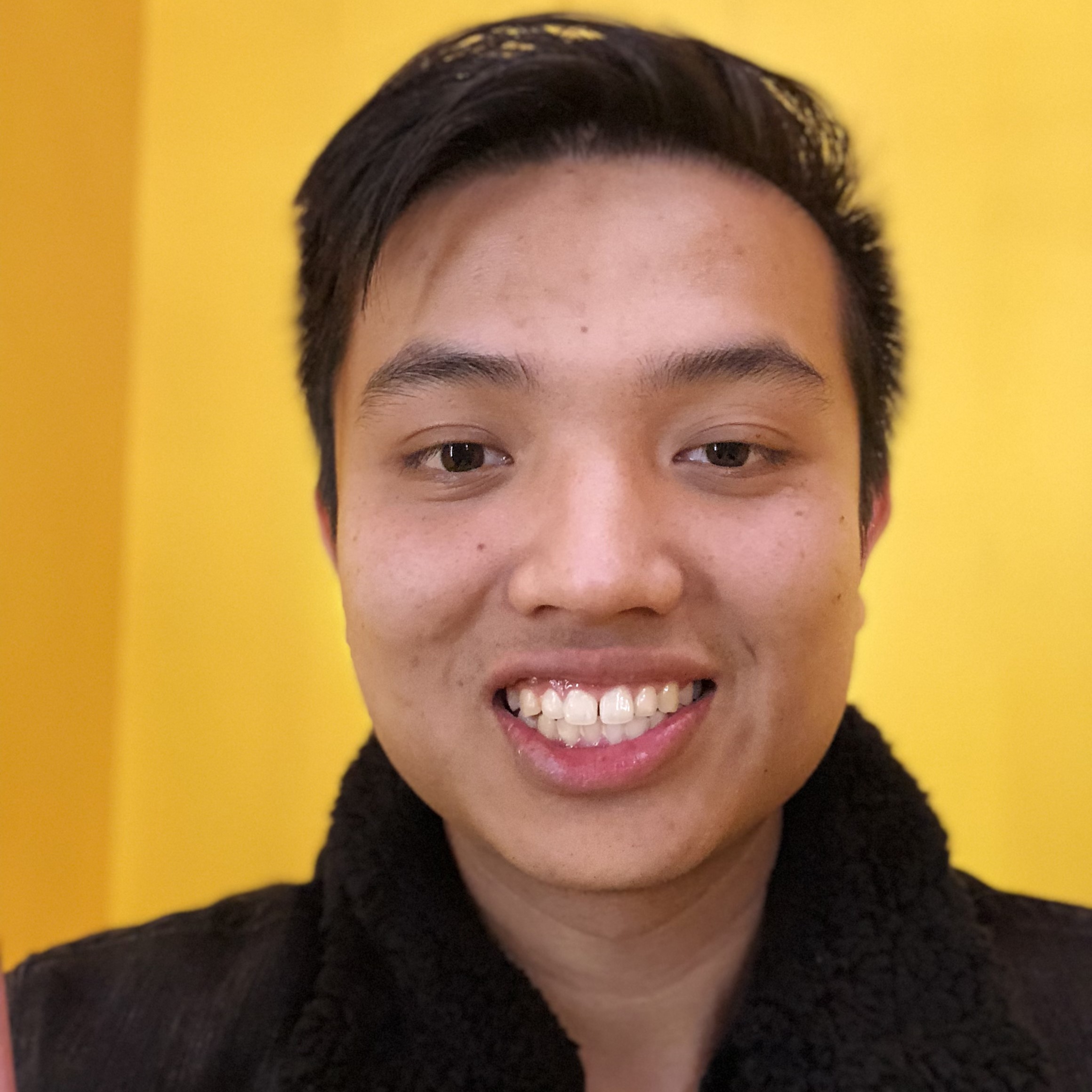 Headshot of former master's student Marvin with a yellow wall in the background