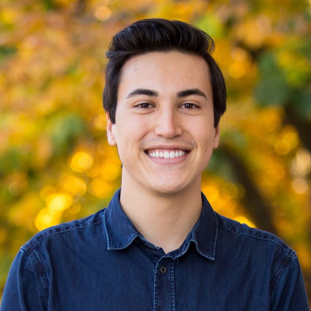 Headshot of former master's student Michael in front of a blurred yellow leaf tree background