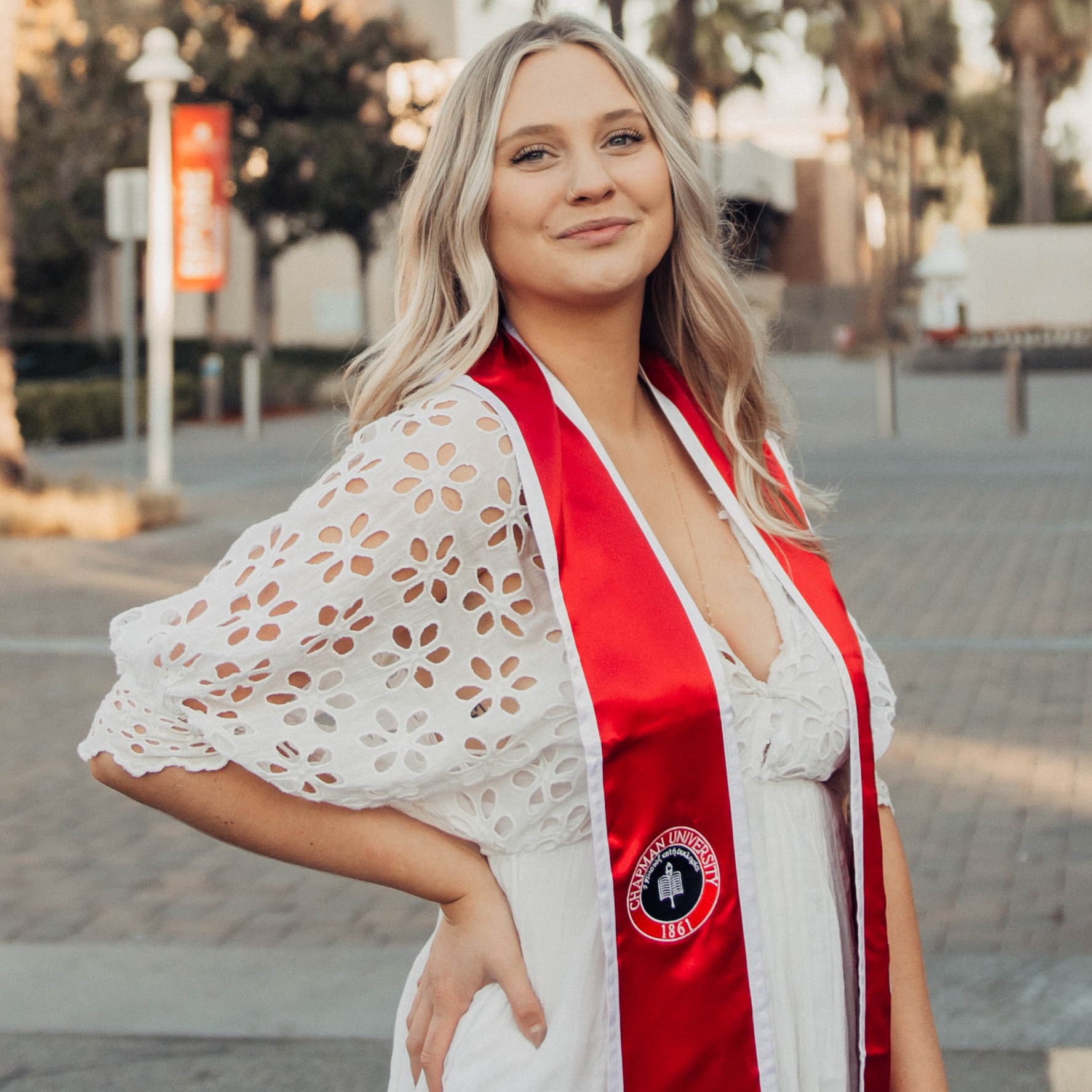 Headshot of research assistant Natalie in a white dress with a red San Diego State University stole on the SDSU campus