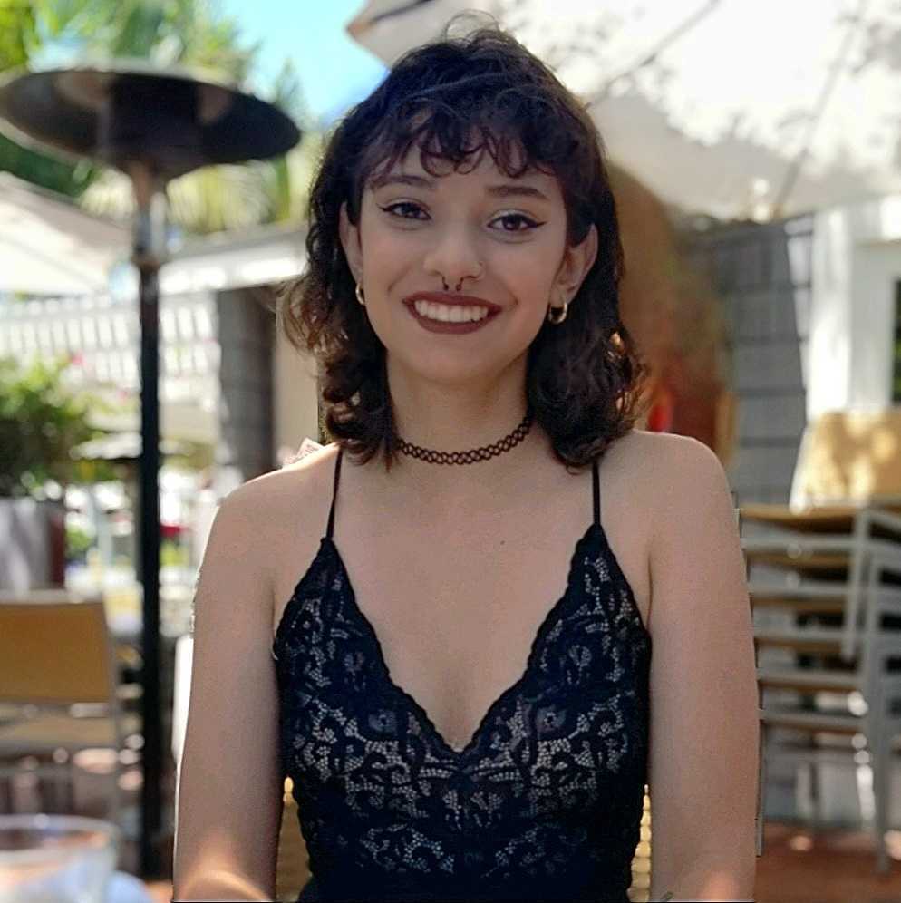Headshot of master's student Alexa smiling outside and wearing a black tank top