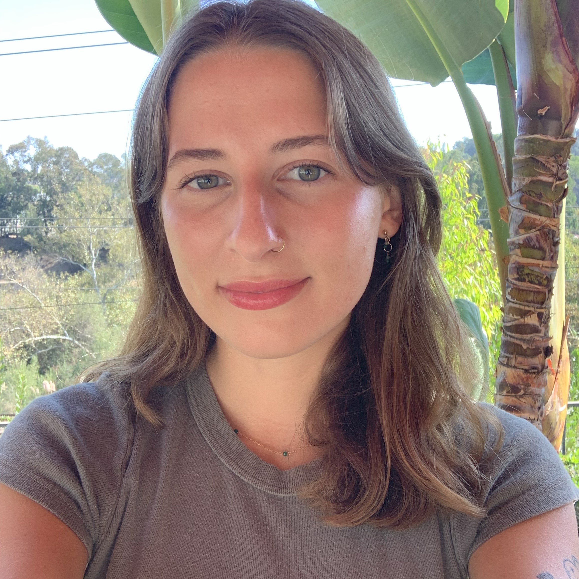 Headshot of project coordinator, Grace, in a grey t-shirt standing outside