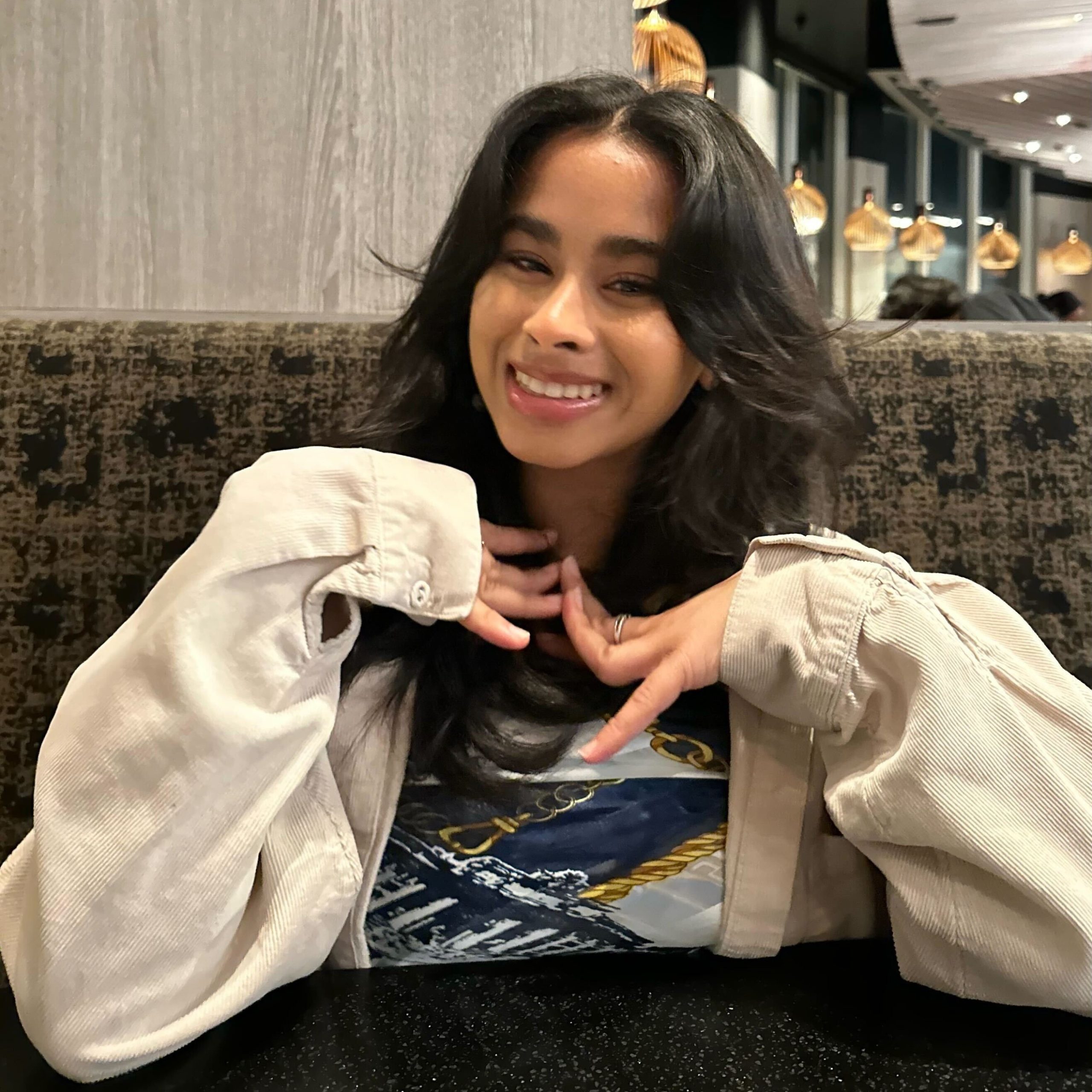 Headshot of research assistant Nami smiling wearing a beige, long-sleeve button up sitting at a table