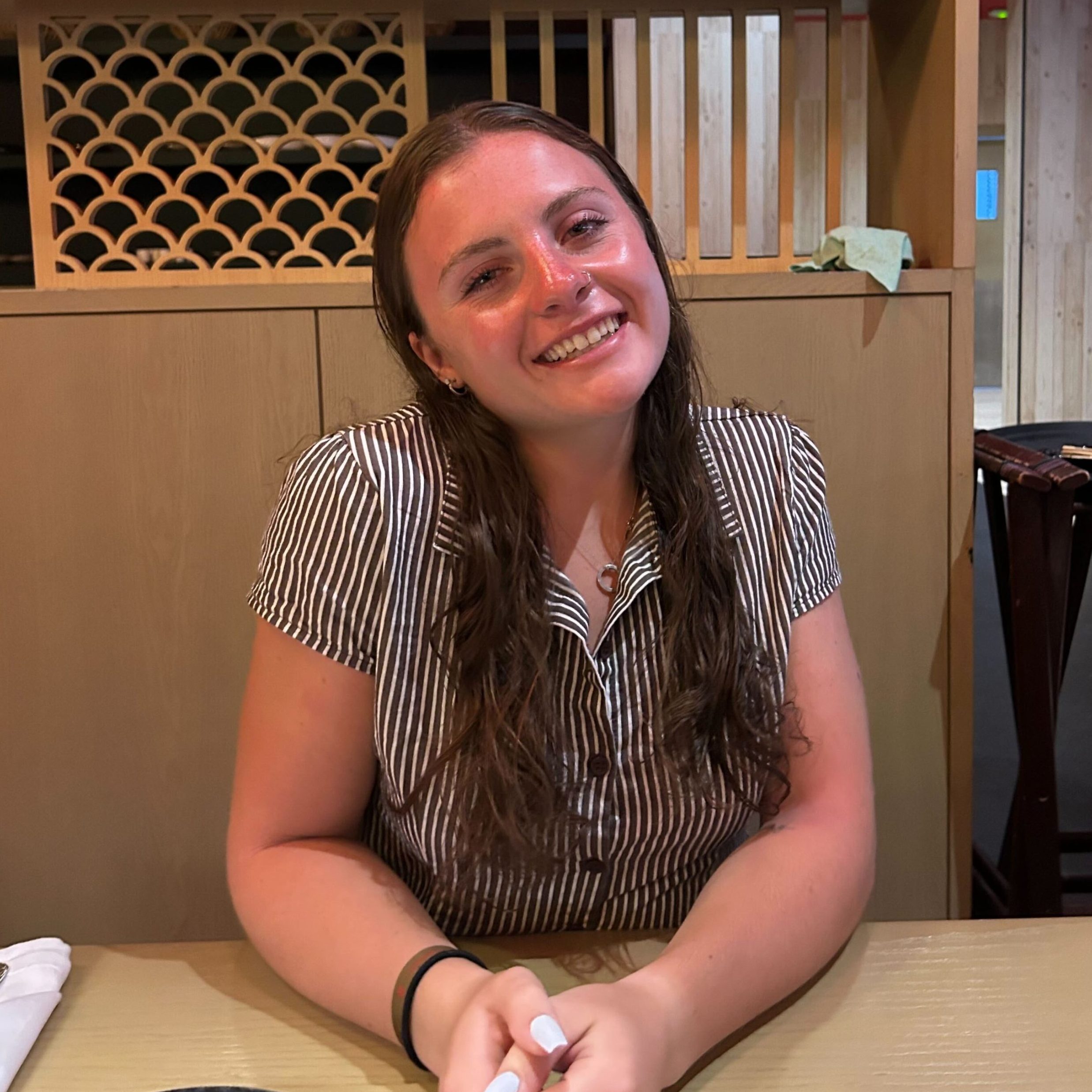 Headshot of research assistant: Jill Peterson sitting down in a striped button up shirt smiling indoors