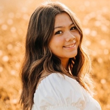 Headshot of research assistant, Myah Tuupo, standing outside wearing a white top while smiling